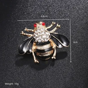 Macro shot of bee brooch with white crystals, red rhinestone eyes and black enamel detail