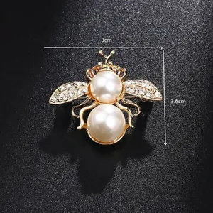 Detail shot of a golden bee brooch with white pearls and sparkling crystal rhinestones
