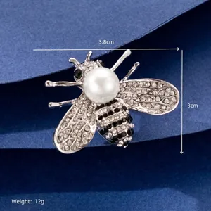 Close-up of a silver bee brooch with sparkling rhinestones and a large pearl center