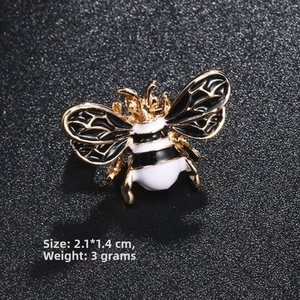 Detail of bee brooch with black and gold filigree wings and white enamel body