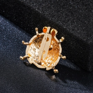 Macro detail of the golden beetle brooch back showing the pin closure and plated finish