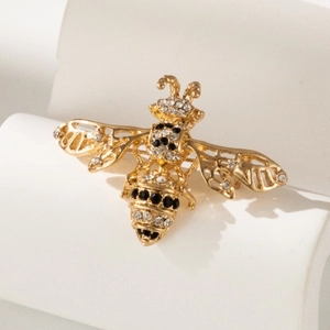 Elegant gold bee brooch with sparkling crystals on a minimalist white background