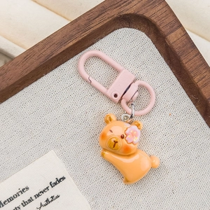 Detail of pink clasp and cute orange resin bear charm with flower on textured fabric