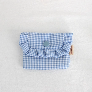 Detail of blue and white plaid storage bag with ruffle trim and button closure