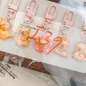 Close-up of five cute pink cartoon bear keychains with matte carabiners on fabric