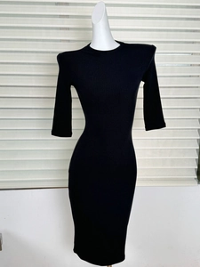 Detail of black ribbed knit dress featuring shoulder pads and slim fit silhouette