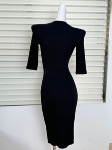 Detail view of the fine ribbed texture and stretchy fabric of a black bodycon midi dress