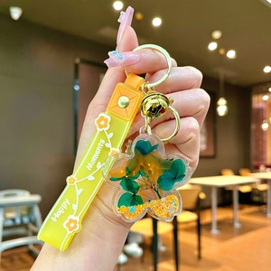 Detail of flower oil keychain with green dried blooms and yellow silicone wrist strap