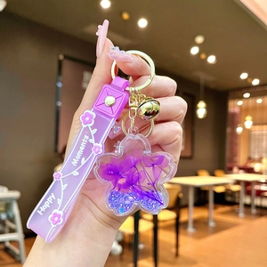 Detail of purple flower resin keychain with Happy Moments strap held in hand