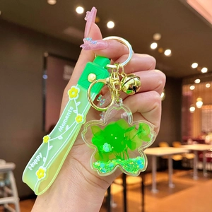 Detail of green floral liquid keychain with silicone handle and golden bell attachment