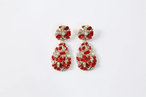 Macro view of teardrop earrings with red faceted crystals and gold alloy setting