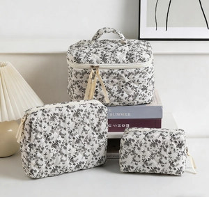 Detailed set of three white quilted floral makeup bags in various sizes with handle
