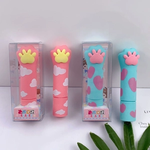 Detail of cat paw lipstick-shaped erasers in pink and blue on a clean desk setting