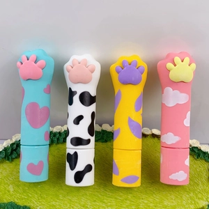 Close-up of four cat paw erasers with cute heart and floral patterns on mini grass
