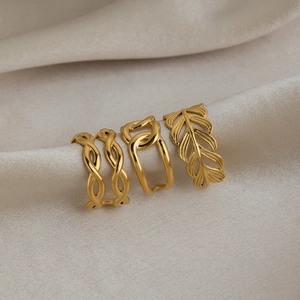 Detailed view of three gold-plated stainless steel rings with wave, chain, and leaf designs