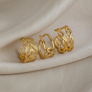 Close-up of three 18K gold-plated stainless steel hollow leaf and twisted rings on silk