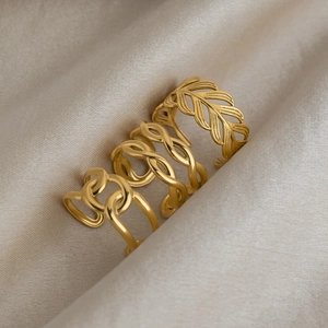 Close-up of three gold-plated titanium steel rings featuring feather and chain link textures