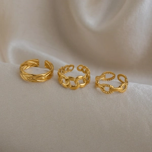 Detailed view of three stackable gold rings featuring woven wheat and chain designs
