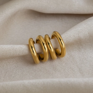 Polished double-layered gold ear cuffs made of stainless steel on beige fabric