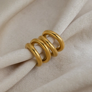 Close-up of gold double-layer round rings on beige textured linen fabric background