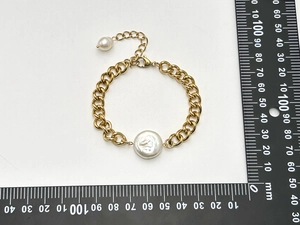 Macro view of gold-plated thick chain bracelet with a large white baroque pearl and scale