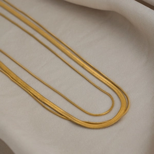Close-up of triple-layered gold snake chain necklaces with polished metal textures