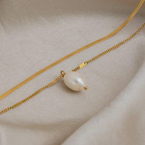 Macro view of double-layer gold stainless steel necklace with baroque freshwater pearl