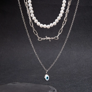 Three-layer layered necklace featuring pearls, silver barbed wire, and evil eye pendant