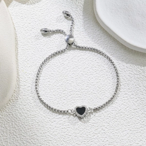 Detail of adjustable silver chain bracelet with heart charm and black enamel inlay