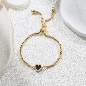 Detail of adjustable gold-plated chain bracelet with a black heart and sparkling crystals