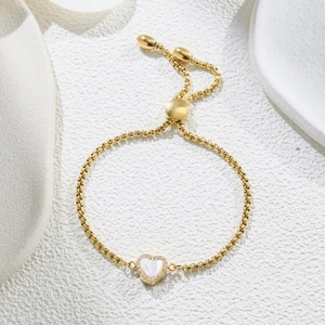 Detail of adjustable gold box chain bracelet with mother of pearl heart charm and zircons