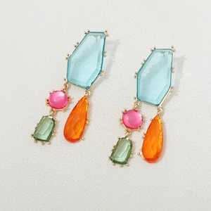 Détail de boucles d'oreilles bohèmes avec cristaux géométriques colorés et monture dorée