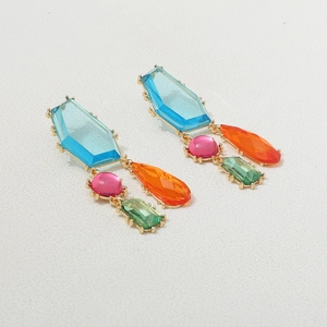 Détail de boucles d'oreilles bohèmes avec cristaux bleus, roses, oranges et verts