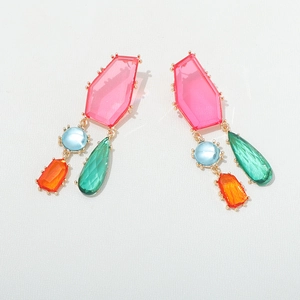 Détail de boucles d'oreilles géométriques en résine colorée avec cristaux et métal doré