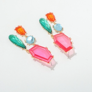 Détail de boucles d'oreilles géométriques en cristal coloré avec base dorée et contrastée