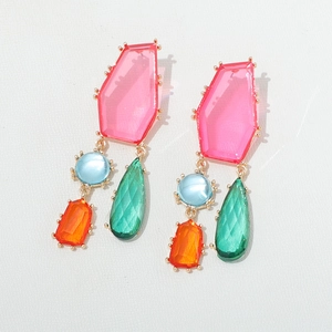 Détail de boucles d'oreilles géométriques avec cristaux roses et pierres vertes