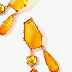 Vue macro de boucles d'oreilles géométriques ambrées avec monture en métal doré