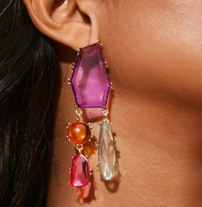Détail de boucles d'oreilles bohèmes géométriques avec cristaux violets et pierres colorées