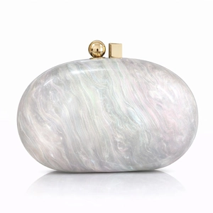 Macro detail of acrylic marble clutch bag with golden geometric clasp and pearl finish