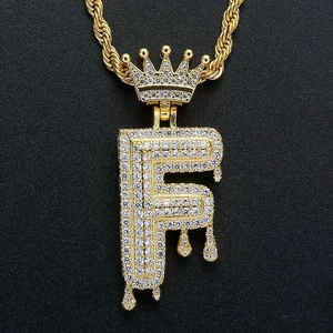 Macro shot of gold hip hop letter F pendant with crown and iced out cubic zirconia stones