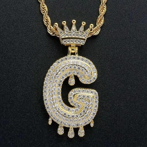 Detail of gold drip letter G pendant with crown and zircon paving on rope chain