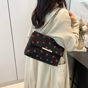 Detail of black corduroy shoulder bag with strawberry print and gold chain strap