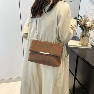 Detailed texture of brown corduroy shoulder bag with red strawberry embroidery and chain