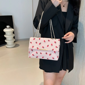 Detailed shot of pink corduroy shoulder bag with strawberry print and gold chain strap