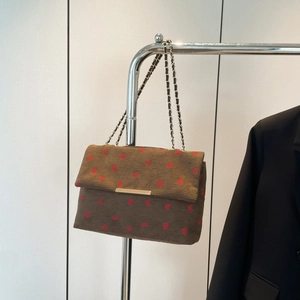 Close-up of brown corduroy shoulder bag featuring strawberry embroidery and chain strap