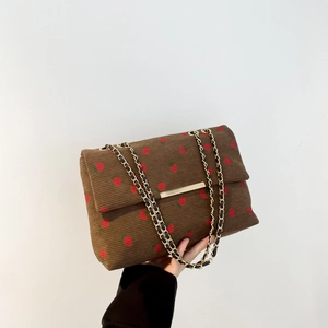 Close-up of brown corduroy shoulder bag with strawberry embroidery and gold chain strap