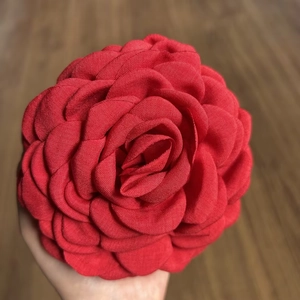 Detailed close-up of a red fabric rose hair claw clip with layered 3D camellia flower petals