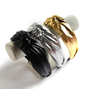 Three PU leather twisted knot headbands in black, metallic silver and gold on a display