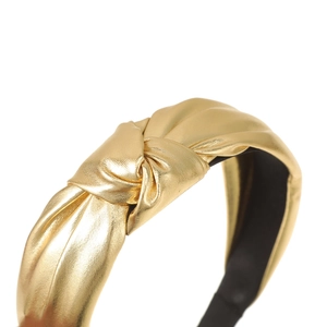 Macro shot of metallic gold knotted headband showing fine brushed texture and knots