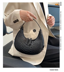 Close-up of black crescent shoulder bag featuring premium crocodile pattern texture